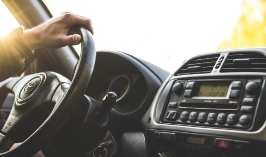 man driving car with one hand on the steering wheel