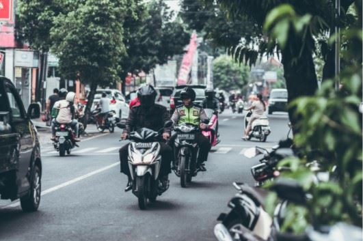 motorcyclists riding down the street next to cars